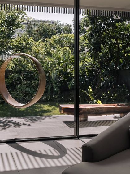A view from inside the living room, looking out at the circular sculpture and the garden. The large glass panels make the outdoor art feel like a part of the interior space.