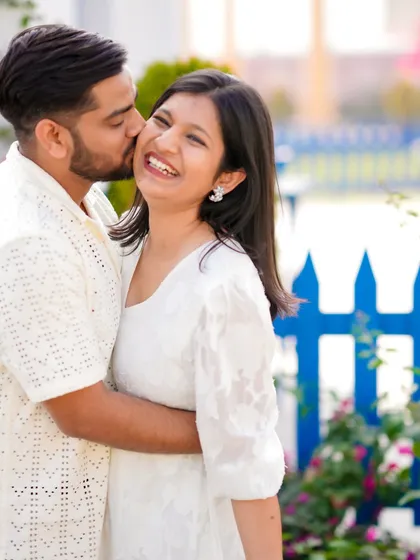 A sweet kiss on the cheek captures the affection and happiness of this couple. Set against a simple, colorful backdrop, this candid shot is all about their natural chemistry.