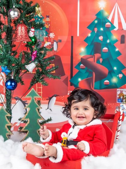A sweet smile from Santa's cutest helper, sitting in her sleigh next to the Christmas tree.
