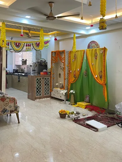 This is a full view of a home I decorated for a pooja. I created a mandap with yellow and green drapes and marigold flower garlands, and also added hanging floral decorations throughout the living room.