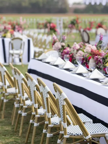 A long view of the dining tables at the polo luncheon, showing the crisp black and white linens against the green polo field. The setup is both elegant and perfectly suited to the outdoor venue.