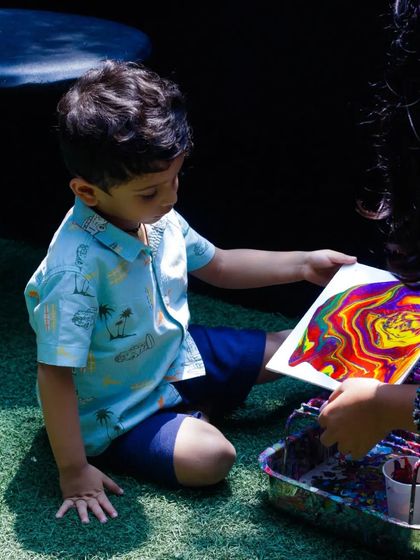 A young artist is mesmerized by the acrylic pour painting he's creating at our Father's Day event. This technique is always a huge hit, as the flowing colors create a unique masterpiece every time.