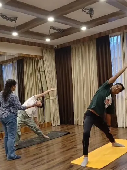 In our small batch classes, you get the guidance you deserve. Here, you can see one of our instructors providing personal alignment correction for Trikonasana (Triangle Pose) during a holistic yoga session. We keep our classes intimate so we can focus on your form and progress.