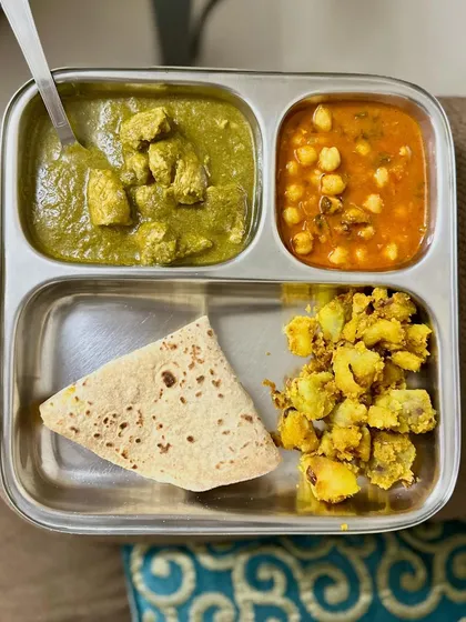 A balanced meal with chicken saag, channa masala, chapati, and sautéed potatoes. This plate combines both animal and plant-based proteins for a nutrient-dense lunch.