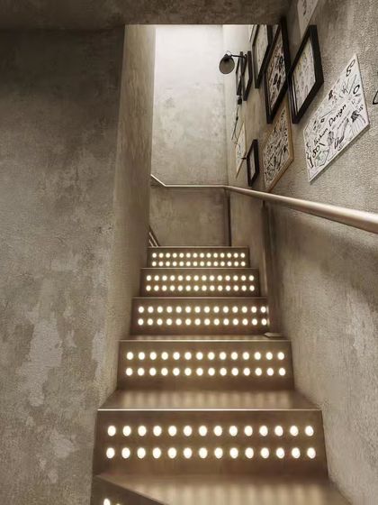 These renders showcase a unique industrial-style staircase with integrated lighting. We highlight the raw concrete walls, the metal steps, and the gallery wall of art to capture the edgy, creative design.