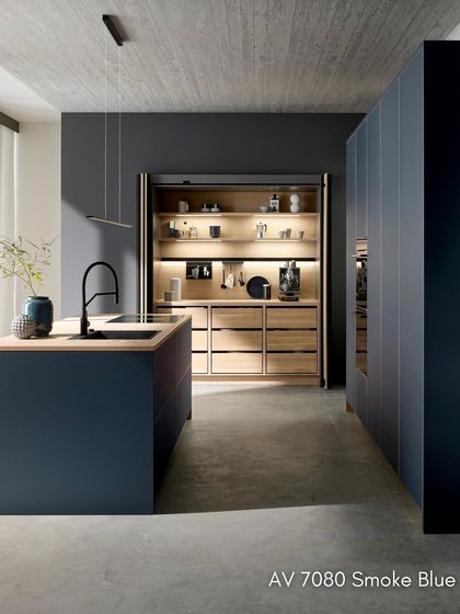 The Systemat AV 7080 kitchen in Smoke Blue, featuring matte linoleum fronts made from sustainable materials. Pocket doors open to reveal a beautifully illuminated oak interior.
