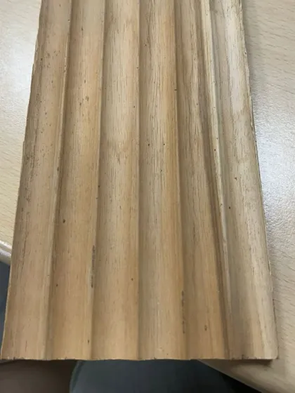 A sample of a solid wood plank with a fluted, wavy profile. This kind of custom milling allows for truly unique wall and ceiling cladding designs.