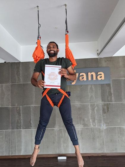 A smiling graduate celebrates completing the teacher training course, hanging joyfully in the hammock.