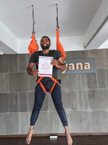 A happy graduate, certificate in hand, ready to share the magic of aerial yoga with others.
