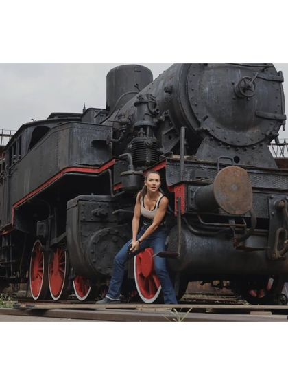 Amy Jackson's character in a full shot against a locomotive on the 'CRAKK' set. This image shows the complete outfit, designed to be practical for an action hero.