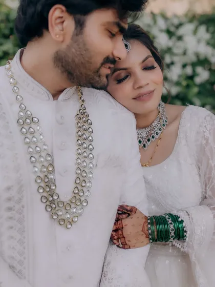 A tender moment between the couple. The bride's elegant makeup complements her modern white lehenga and the groom's classic attire.