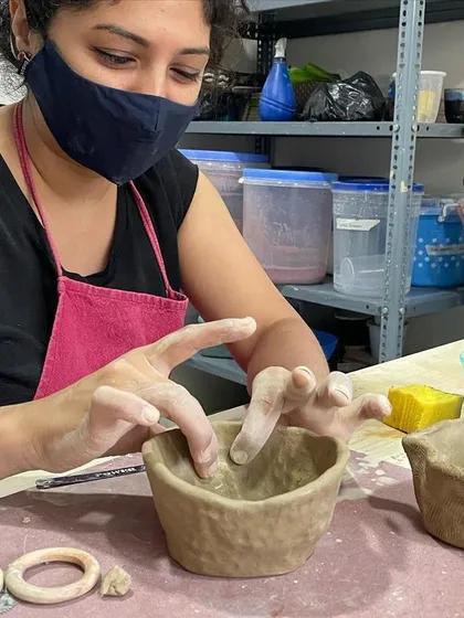 A student deep in concentration, shaping the rim of her pinch pot.