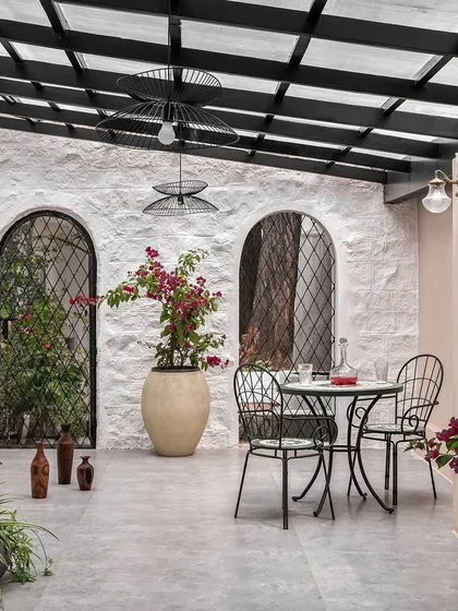 The spacious patio was designed to feel like a Mediterranean courtyard. With its rough-textured walls, arched niches, and plentiful greenery, it’s a versatile space for relaxing or entertaining.