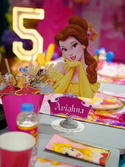 A detailed look at the themed table setting, featuring a centerpiece of Princess Belle. Every element is carefully chosen to match the royal theme.
