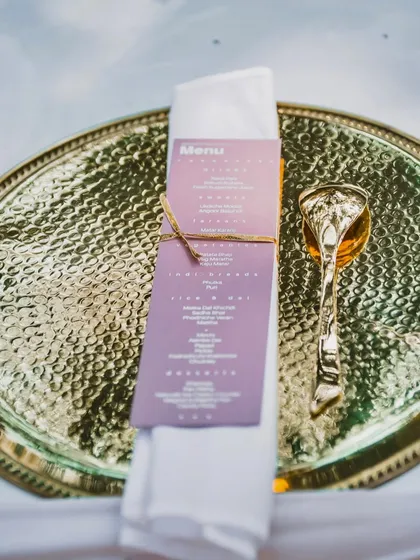 It's the little details that make an event special. This image shows a personalized menu tied with twine to a napkin, placed on a hammered golden thali, showcasing my attention to detail in table settings.