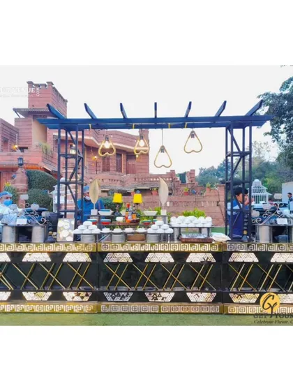 A wide shot of an outdoor buffet counter, elegantly designed and set against the backdrop of a beautiful venue.