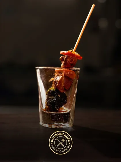 A single skewer with grilled chicken and broccoli presented in a shot glass. A stylish and convenient way to serve delicious appetizers.