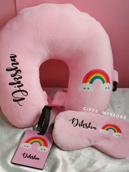 A travel comfort set including a personalized neck pillow, eye mask, and luggage tag, all in a cute pink rainbow theme.