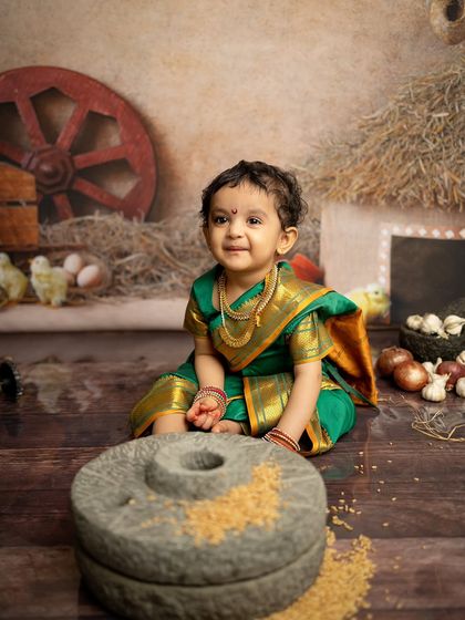 A sweet, smiling portrait from the Maharashtrian village session. The soft lighting highlights her adorable expression and the beautiful details of her green saree.