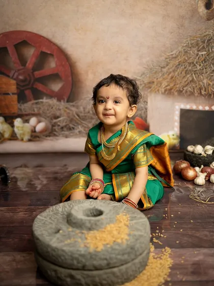A sweet, smiling portrait from the Maharashtrian village session. The soft lighting highlights her adorable expression and the beautiful details of her green saree.