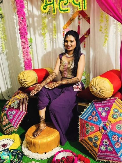 A full-length shot of the client at her colorful mehandi setup, showcasing both her hand and foot henna.