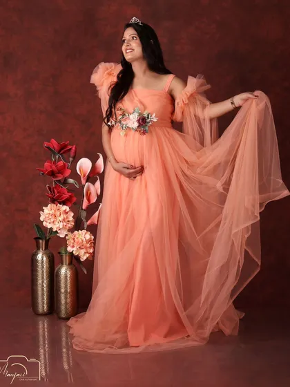 A princess moment. Wearing a delicate tiara and a flowing peach gown, this mama-to-be looks absolutely radiant and full of joy.