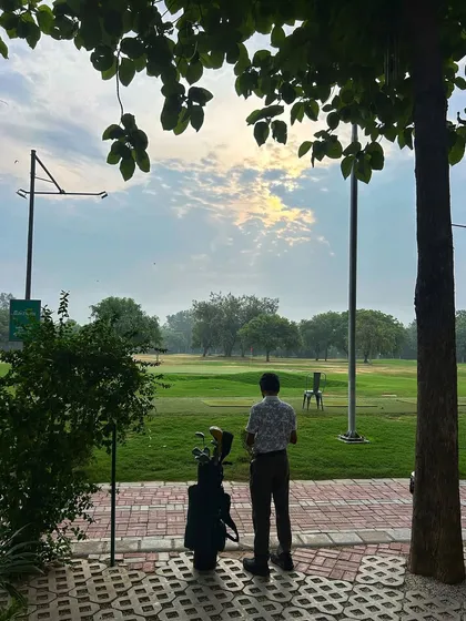 A lone golfer takes in the view of the range before starting his session, a perfect moment of calm.