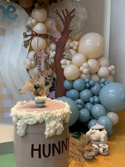 A detailed shot of the "Hunny" barrel cake stand and the whimsical balloon tree with Tigger and Pooh swinging from a branch.