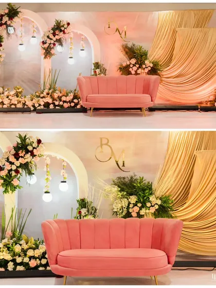 The main stage decor for an engagement, featuring elegant arches, hanging lights, and beautiful floral arrangements flanking a stylish pink sofa.