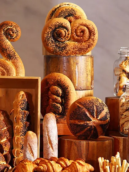 An artistic display of various artisan breads, including intricately shaped loaves and classic baguettes. Our bread baskets are a testament to our belief that even the simplest elements should be beautiful.