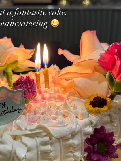 A photo from a client's celebration, showing the beautiful flower garden cake lit with birthday candles. "What a fantastic cake, mouthwatering," they said!