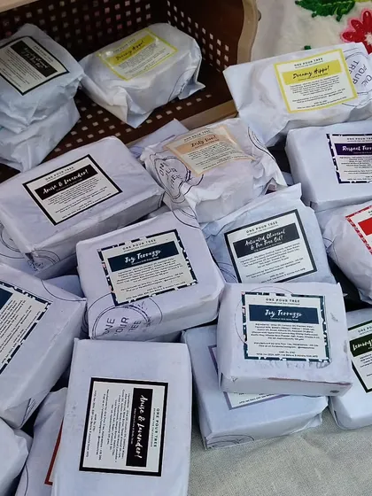 A basket full of freshly wrapped soaps, ready for a market day. Each one is labeled with its ingredients and name.