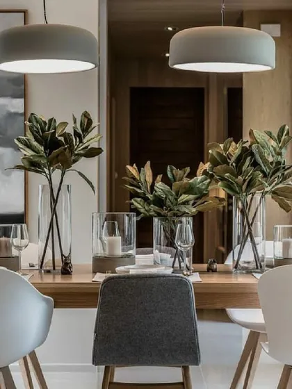 A beautifully set dining table, showcasing how we help with the final decor touches. The simple wooden table is elevated with modern chairs, elegant glassware, and minimalist pendant lighting.