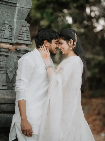 An intimate moment from a traditional pre-wedding shoot. The soft smiles and gentle touch, combined with classic ethnic attire against ancient stone, create a feeling of timeless love rooted in heritage.