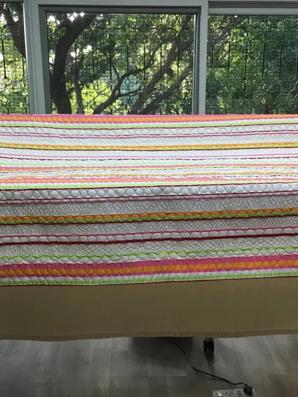 A brightly striped quilt draped over a bed.