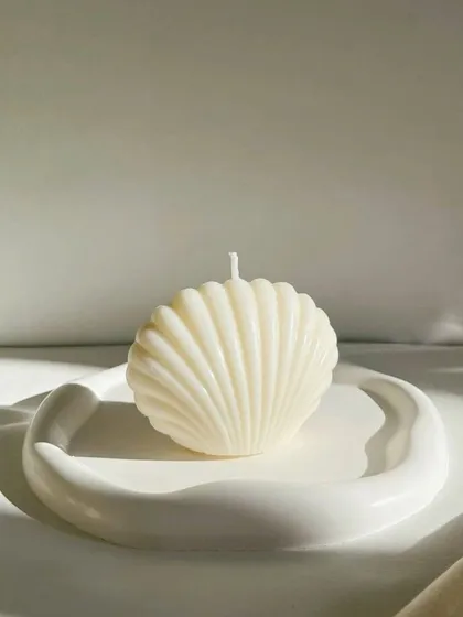 Our unscented shell candle, resting on a modern, abstract trinket tray. A perfect piece of decor for a serene, minimalist aesthetic.