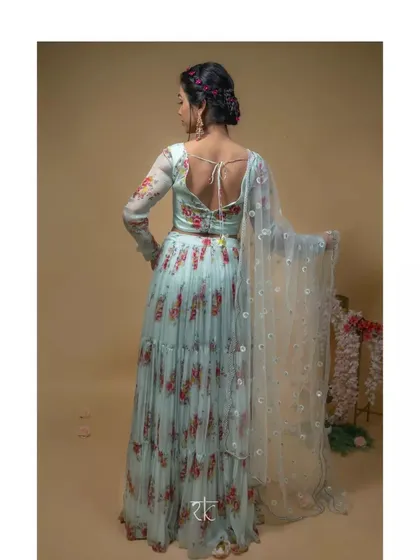 The back view of the baby blue floral lehenga, showing the elegant tie-back detail on the blouse and the graceful flow of the tiered skirt and dupatta.
