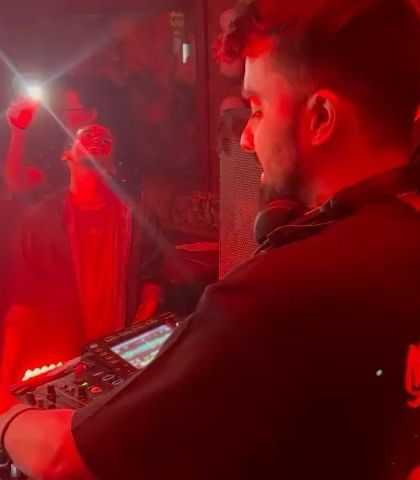A close-up shot from behind the console, bathed in red light. This captures the intensity and focus required during a set.
