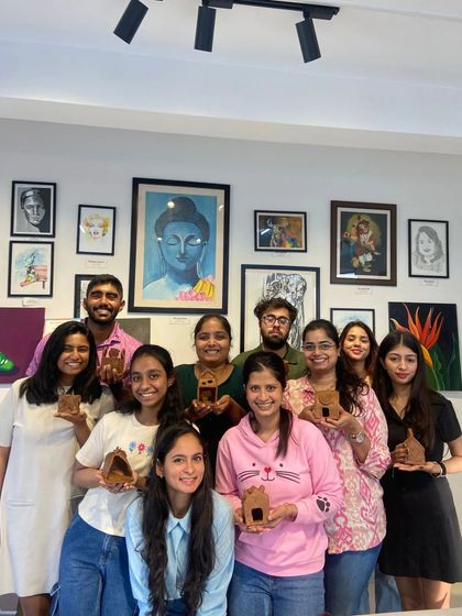 A happy group of participants showing off the small clay houses they made in a handbuilding workshop. It's a fun and whimsical project for all skill levels.