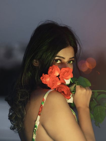 A playful and mysterious portrait, peeking over the roses. The blurred background keeps the focus on her expressive eyes.