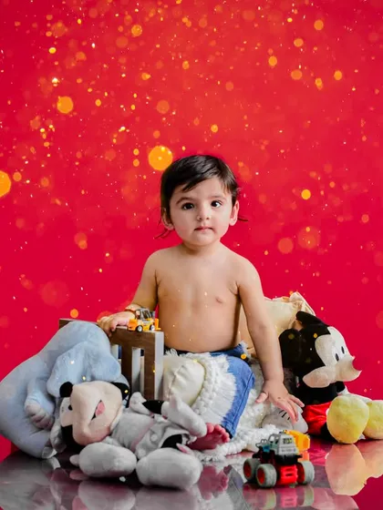 This little boy is ready for his close-up. A vibrant red background and a collection of his favorite toys make for a fun and personal portrait session.
