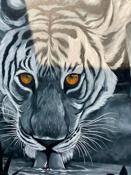 This image captures the tiger's face and paws at the water's edge. The composition is designed to draw the viewer in, creating an intimate and powerful moment with the majestic animal.