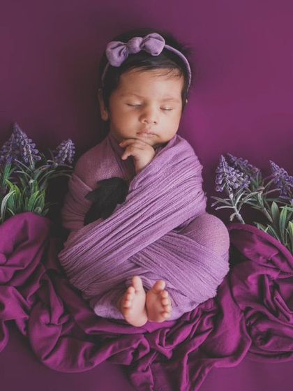 A study in purple. This newborn is wrapped snugly and surrounded by lavender, creating a calming and beautiful color-coordinated portrait.