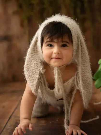 A baby crawls towards the camera wearing an adorable fuzzy bunny bonnet. A perfect outfit for a whimsical toddler shoot.