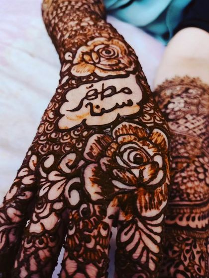 A close-up of a bridal design with the couple's names written in beautiful calligraphy on the palm.