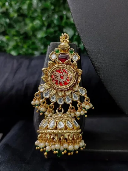 A detailed shot of the matching jhumka earring, showcasing the red pendant and kundan work that ties the whole bridal set together.