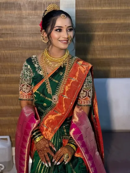 A smiling bride in a green and red Paithani saree, looking radiant and ready for her wedding.