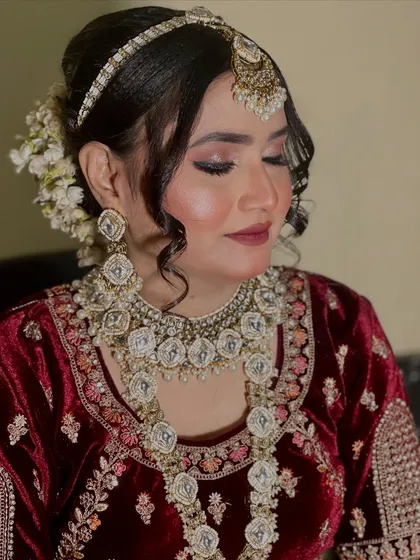 A close-up showing the hairstyle with fresh white flowers tucked into the bun, adding a touch of natural elegance to the glamorous look.