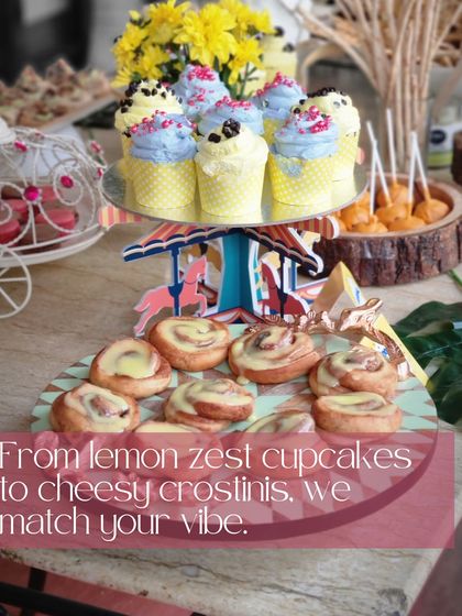 A whimsical dessert display for a baby shower, featuring colorful cupcakes and cinnamon rolls on a carousel stand. We love matching our sweet treats to your party's vibe, from lemon zest cupcakes to cheesy crostinis.