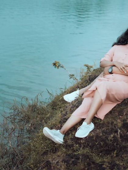 A relaxed, candid portrait of a couple sitting by the lake. This shows a more casual and natural approach to pre-wedding photography, focusing on comfort and ease.